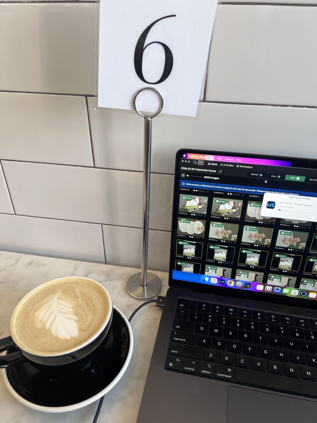 Coffee beside a laptop showing a photo editing session